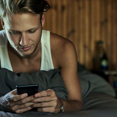 guy-in-bed-boy-man-looking-at-phone-iphone-porn-kills-love